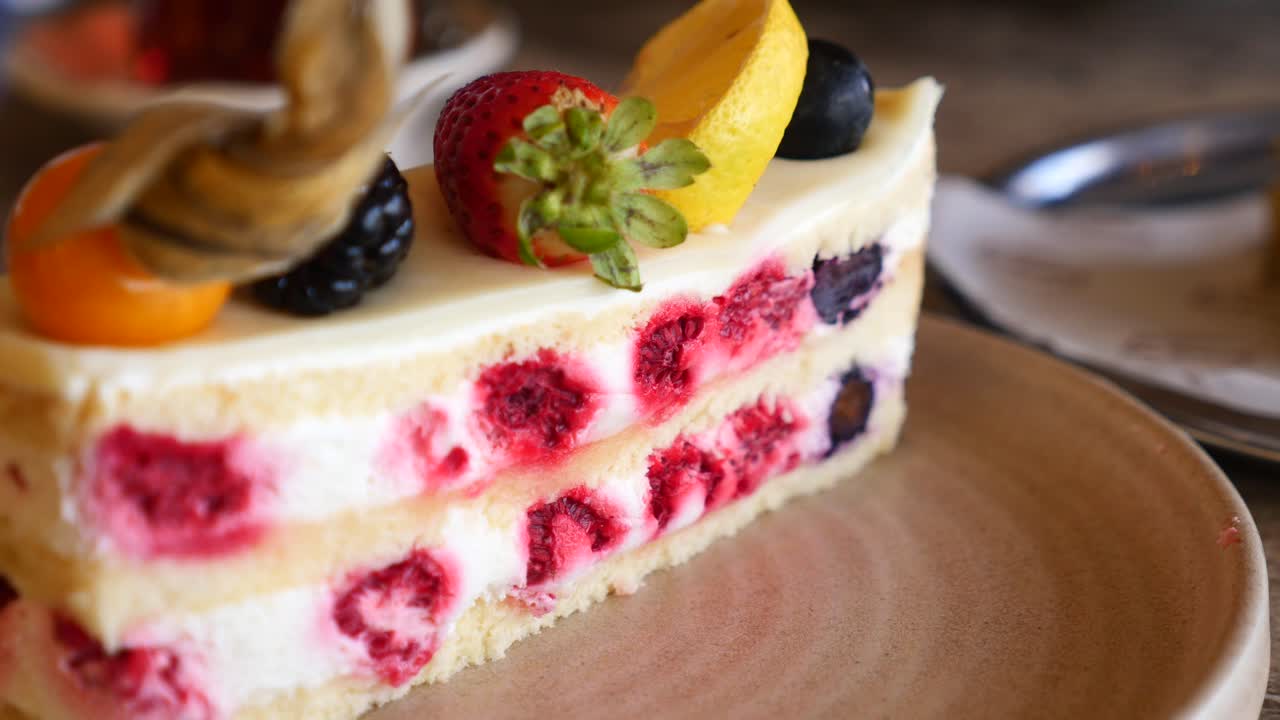 Deliciosa fatia de bolo de frutas vermelhas em camadas com frutas frescas.
