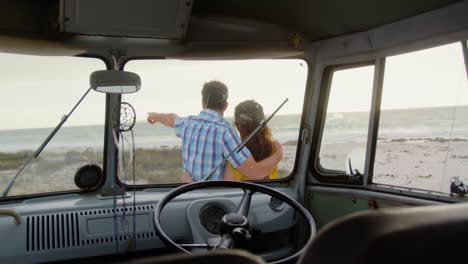 couple standing near camper van on the beach 4k