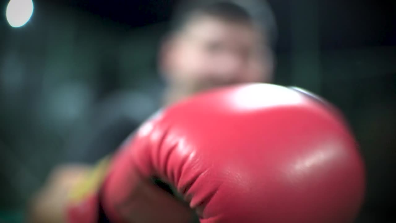 Pugile che sferra jab e pugni con guantoni da boxe verso la telecamera al rallentatore con profondità di campo ridotta