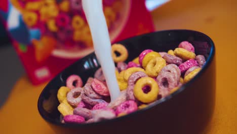 colorful cereals in a bowl with pour out milk in slowmotion