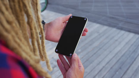 mixed race man with dreadlocks standing in the street using smartphone