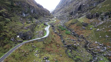 Cinematic-drone-shot-moving-throught-the-Gap-of-Dunloe-Ireland,-through-the-rocky-cliff-walls-with-a-road-in-the-valley
