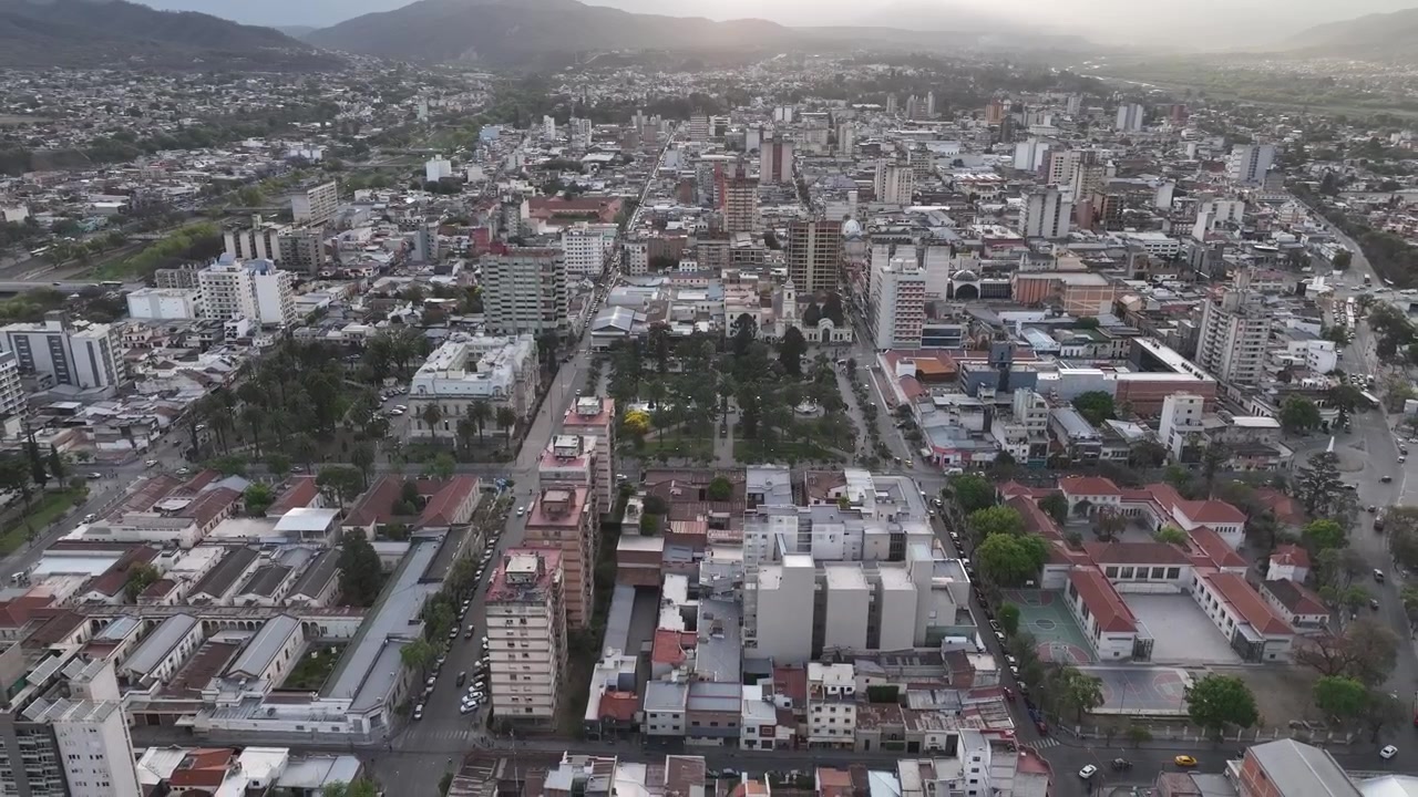 Una vista panoramica aerea rialzata e in allontanamento mostra gli edifici della città di Salta, in Argentina, al tramonto, con le montagne sullo sfondo