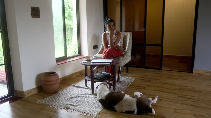 Una donna seduta in una stanza accogliente con il suo cane che si rilassa sul pavimento lì vicino.