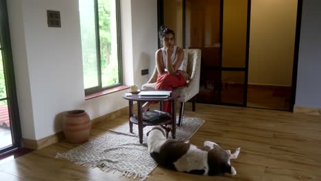 A-woman-sitting-in-a-cozy-room-with-her-dog-relaxing-on-the-floor-nearby