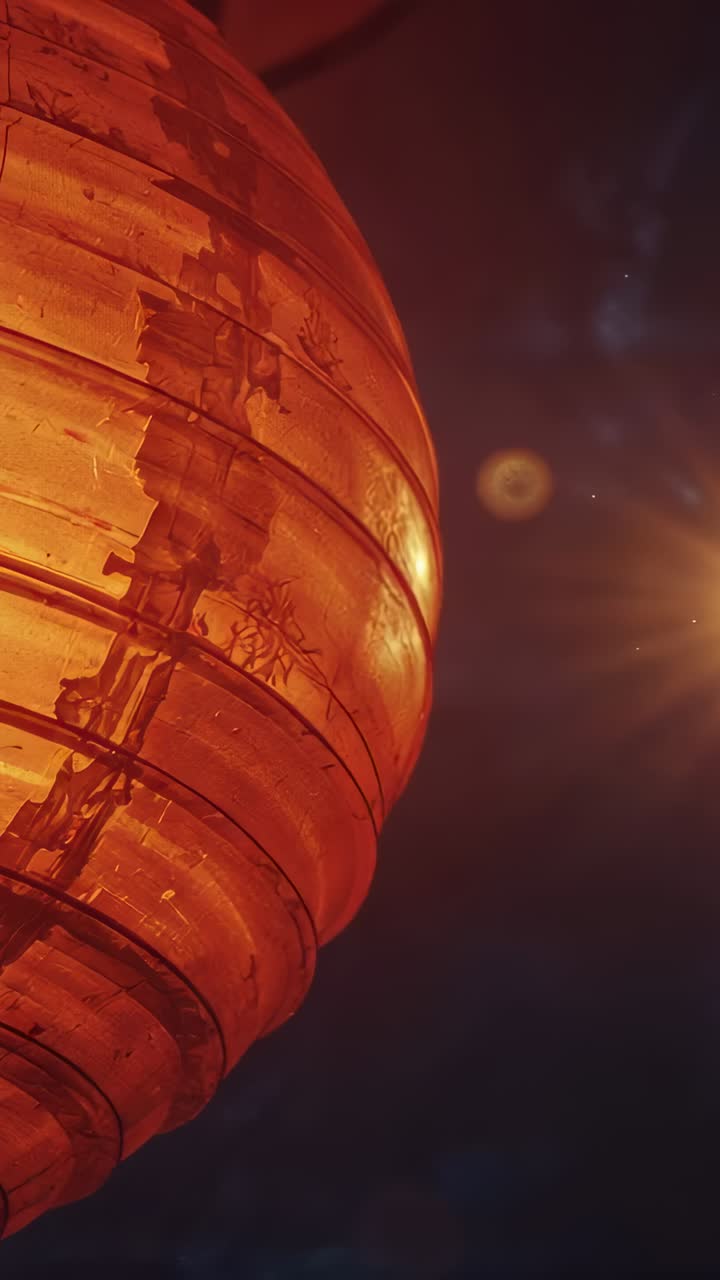 Vertical video: Camera shifting orange lantern swaying, revealing motifs at night, with bulb flare
