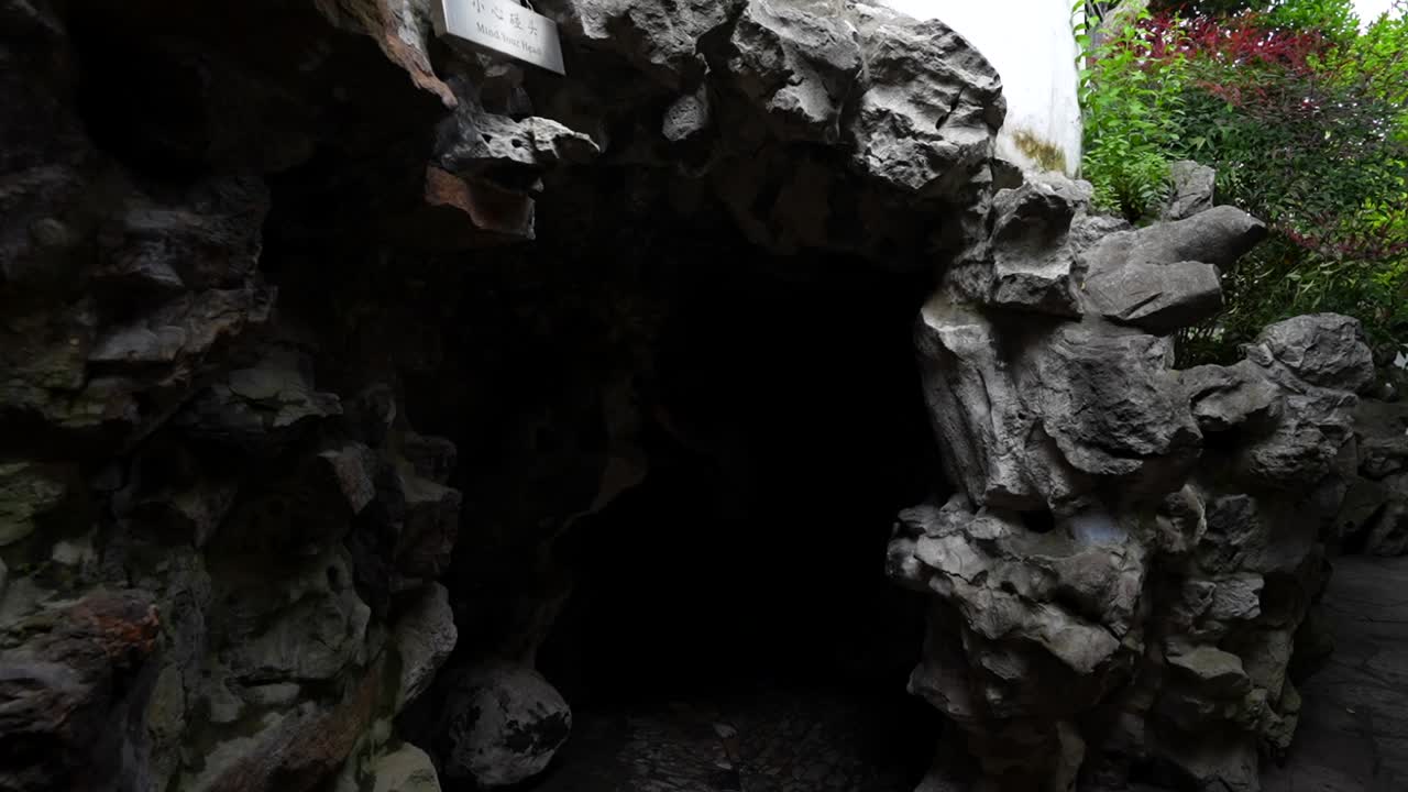 Slow motion of a tourist entering a cave passage that leads to another area of Yuyuan Garden in Shanghai, China
