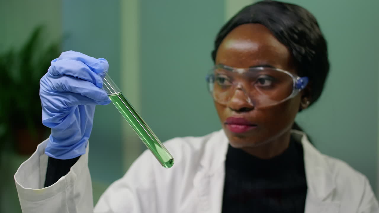 Donna biologa che tiene in mano una provetta con liquido genetico che esamina un campione di DNA verde