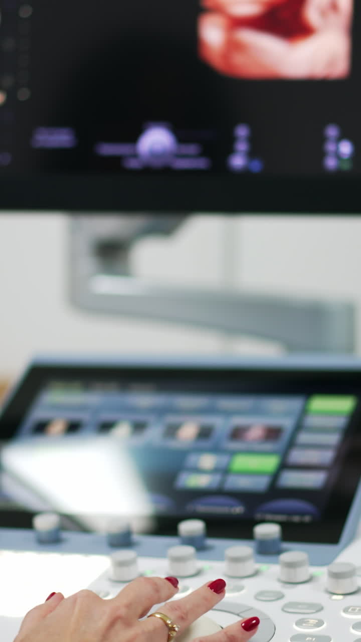 Female doctor sonographer performs ultrasound diagnostic. Specialist looking at the screen with a baby depicted picture on.