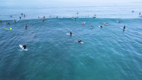 aerial of lots of surfers waiting for waves at waikiki beach honolulu hawaii in bright blue water, aerial orbit