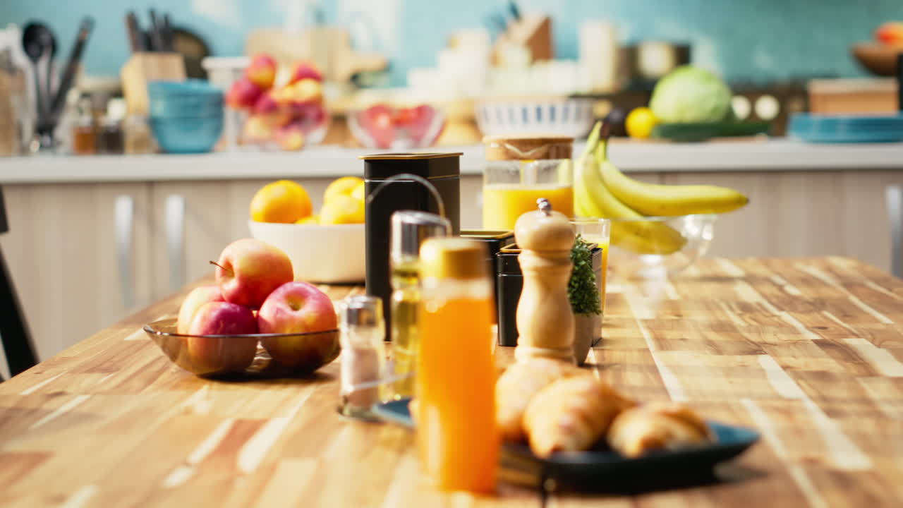 Kitchen scene with fruit, juice, and croissants on a wooden table