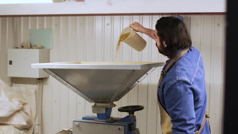 man introducing malt in malt mill