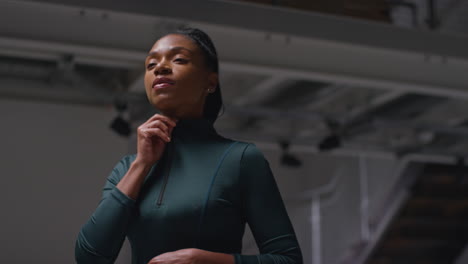 Portrait-Of-Determined-Female-Athlete-Zipping-Up-Tracksuit-Training-In-Gym-Or-Changing-Room-Preparing-For-Sports-Event