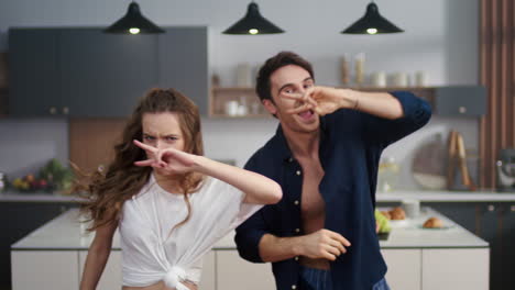 amigos riendo divirtiéndose en la cocina doméstica. pareja feliz bailando en el interior.