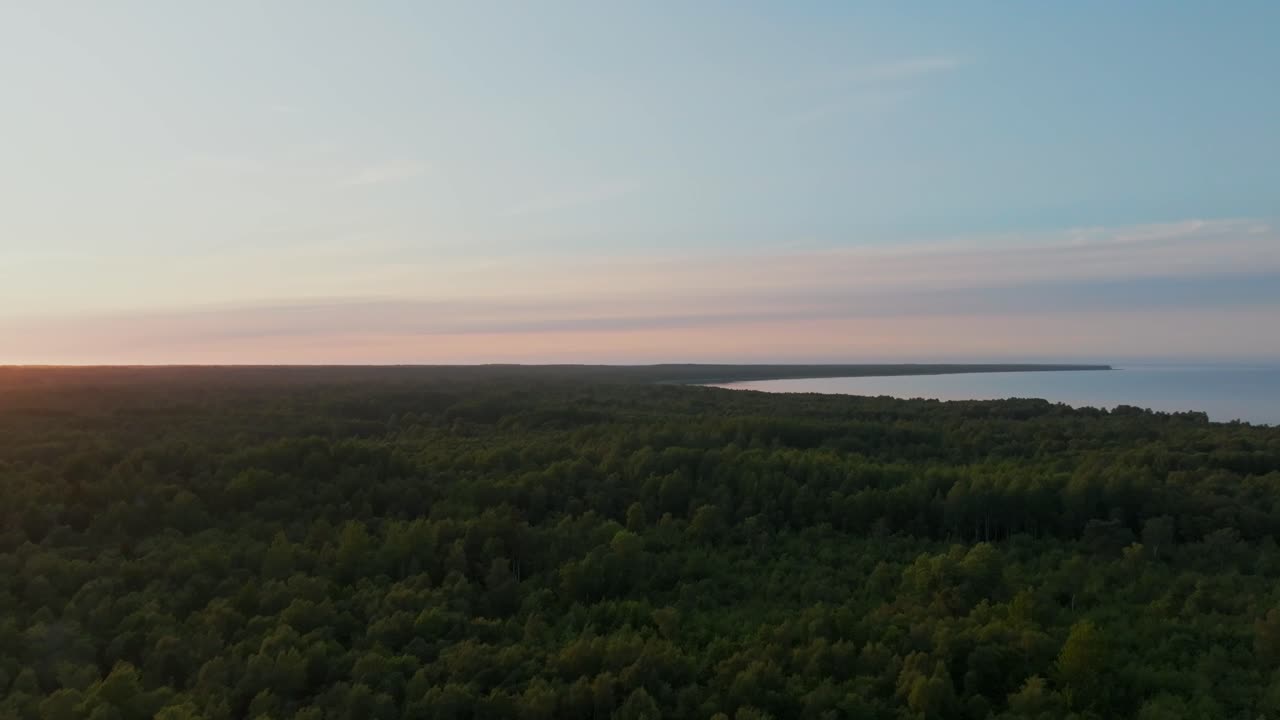 Flying over a forested coastal landscape at evening light, moving from left to right.