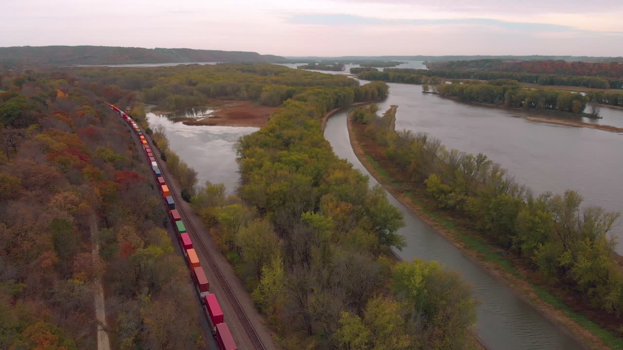 vista aérea del tren de carga con cientos de automóviles transportados a través de los bosques otoñales de illinois.