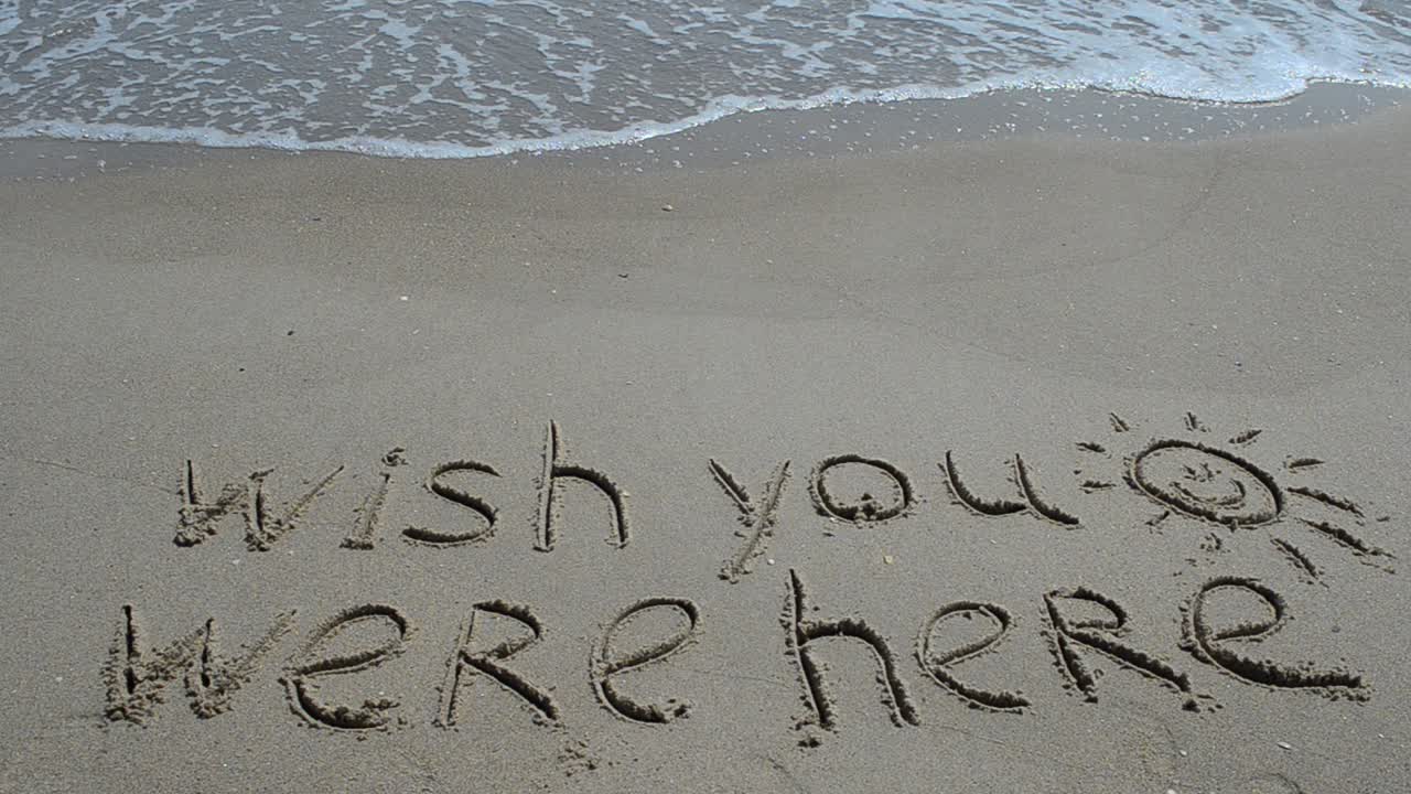 Konceptuel "gid du var her" tekst håndskrevet i sand på en strand. Optagelse på stranden.