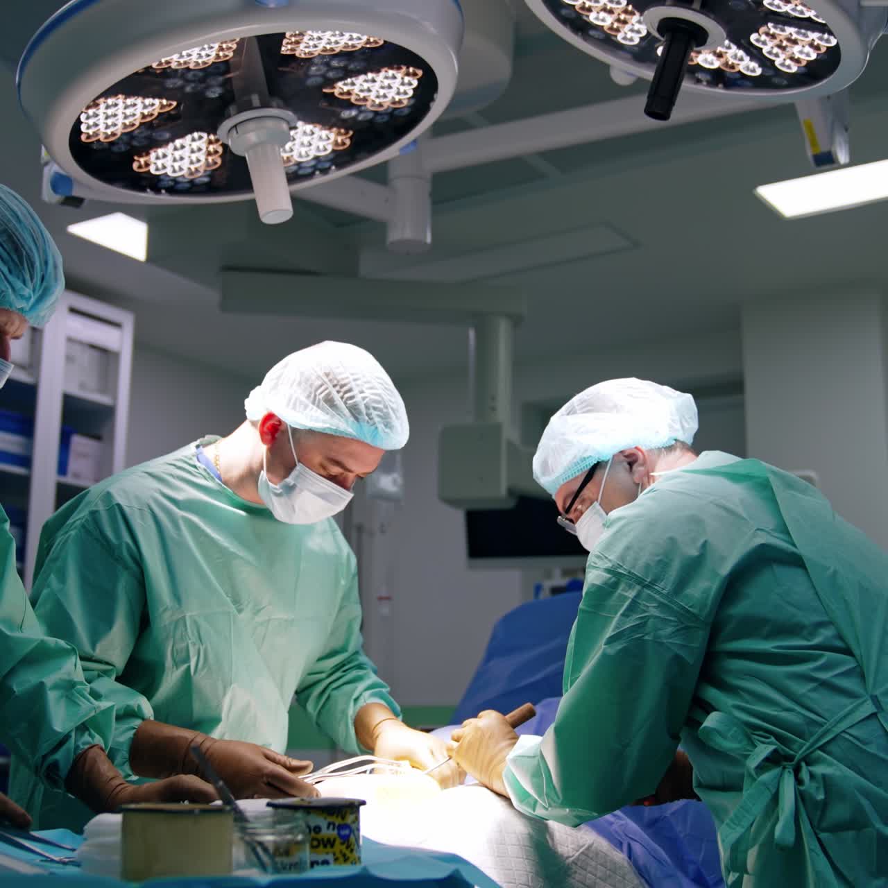 Due medici collaborano a un'operazione in una moderna sala operatoria. Il chirurgo principale usa un martelletto per colpire lo scalpello.