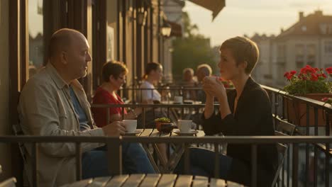 couple enjoys coffee on a city balcony cafe during golden hour