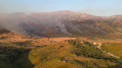 Aerial-footage-of-dramatic-wildfires-burning-in-the-mountains-on-the-outskirts-of-the-city-of-Vlorë,-Albania,-at-sunset