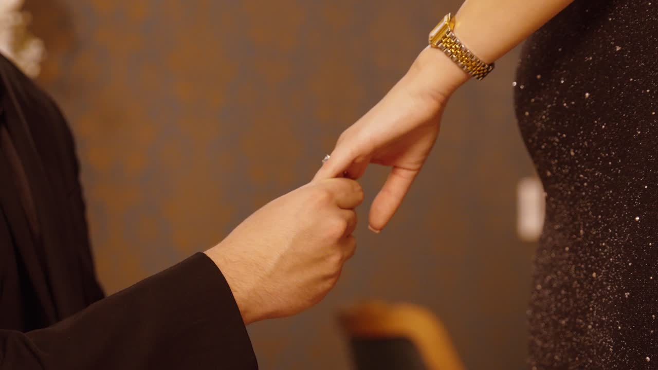 Close-up of a man placing a ring on a woman’s finger during a romantic proposal. Emotional and intimate moment captured in warm lighting
