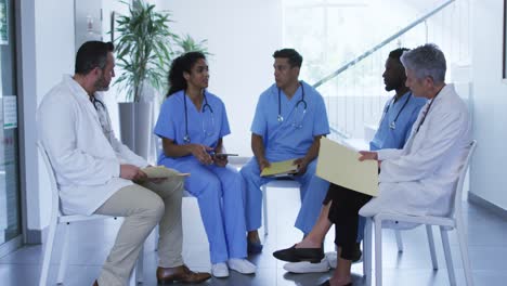 Diverse-female-and-male-doctor-sitting-and-discussing-at-hospital-staff-meeting