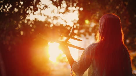 a child plays a plane at sunset silhouette of a girl in the rays of the orange sun