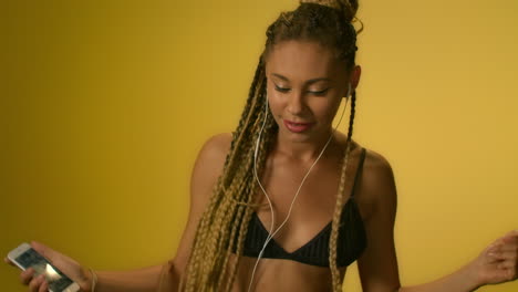 happy woman playing music on mobile phone in studio. afro girl dancing