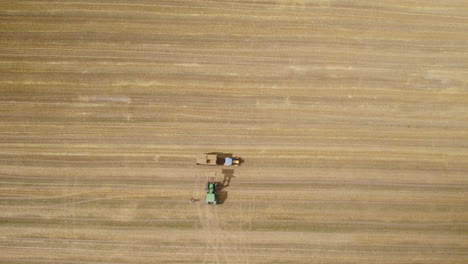 farmers pile up the load of square hay bales in tractor trailer, bird's eye view