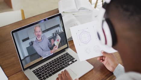 African-american-businessman-sitting-at-desk-using-laptop-having-video-call-with-male-colleague