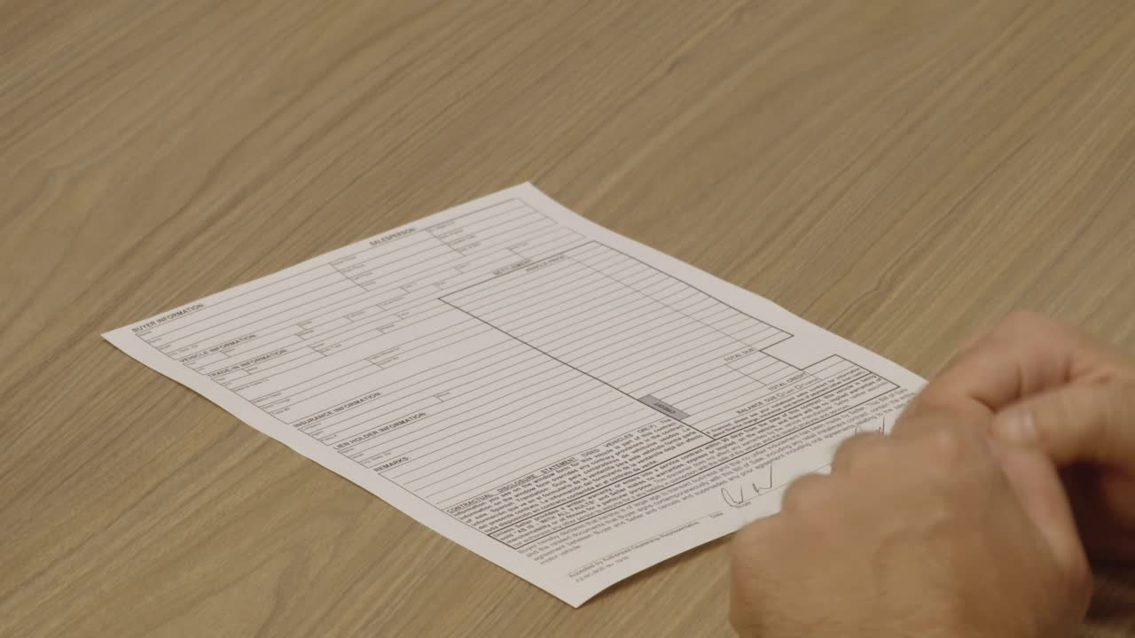 primer plano de un cliente que firma un contrato de venta y recibe las llaves de su nuevo coche