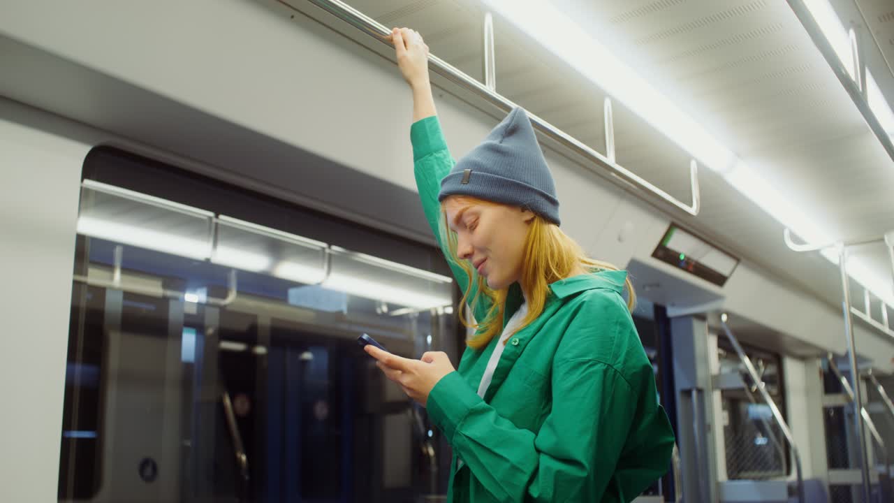 A woman using her mobile phone on a subway train