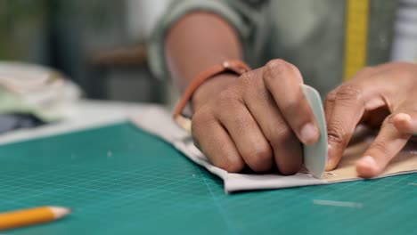 vista de cerca de la mujer sastre sentada en la mesa dibujando líneas en el boceto de la ropa en el taller de costura 1