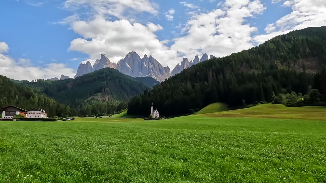 Chiesa di Santa Maddalena con le Odle e un prato verde nelle Dolomiti, Italia