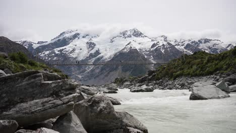 Mueller-River-Mt-Cook-Neuseeland-Fließendes-Wasser-Unter-Der-Brücke-Mit-Gebirgigem-Hintergrund