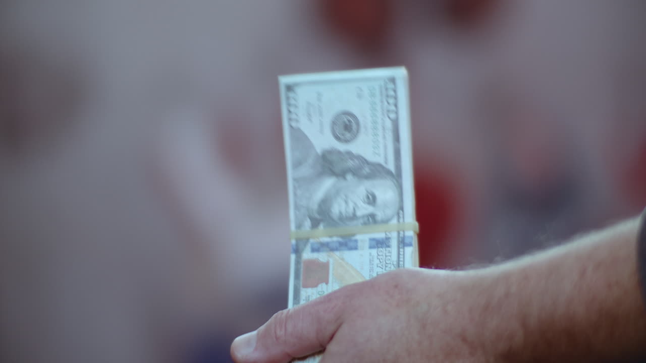 primer plano en cámara lenta de una persona agitando un fajo de dinero de utilería con una banda elástica