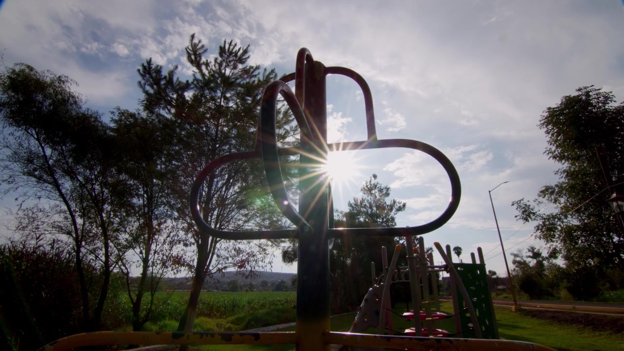 Klimrekken op een speeltuin in tegenlicht in een zonnig park, met bomen, gras en sterke zonne-overstraling die een warme buitenrecreatiescène creëren