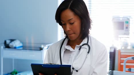 Portrait-of-female-doctor-writing-on-clipboard