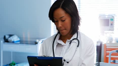 portrait of female doctor writing on clipboard