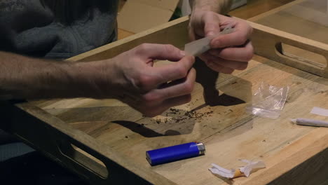 un hombre tomándose su tiempo para liar un porro con marihuana en la comodidad de su casa