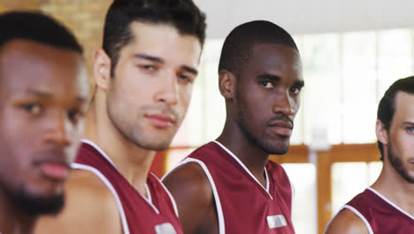 confident basketball players holding basketball in court