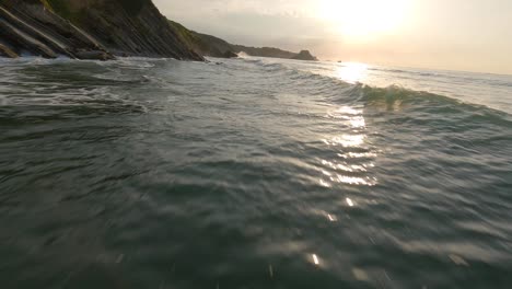 Racing-drone-flying-at-low-altitude-over-sea-waters-along-rocky-cliffs,-Pyrenees-Atlantiques-in-France