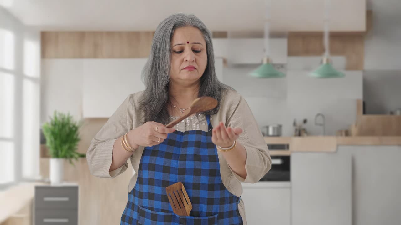 Ama de casa india de edad avanzada cocinando comida picante