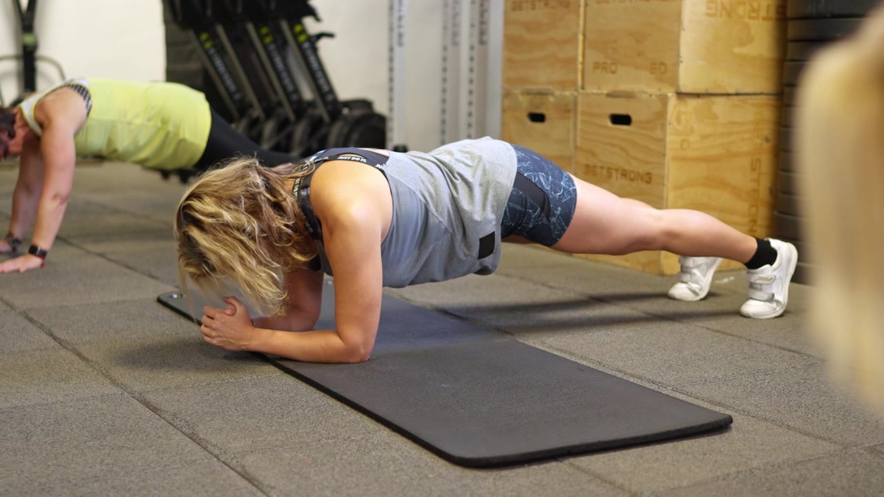 Duas Mulheres Fazendo Exercícios de Prancha em uma Academia