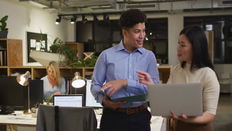 biracial man and asian woman discuss business work in an office