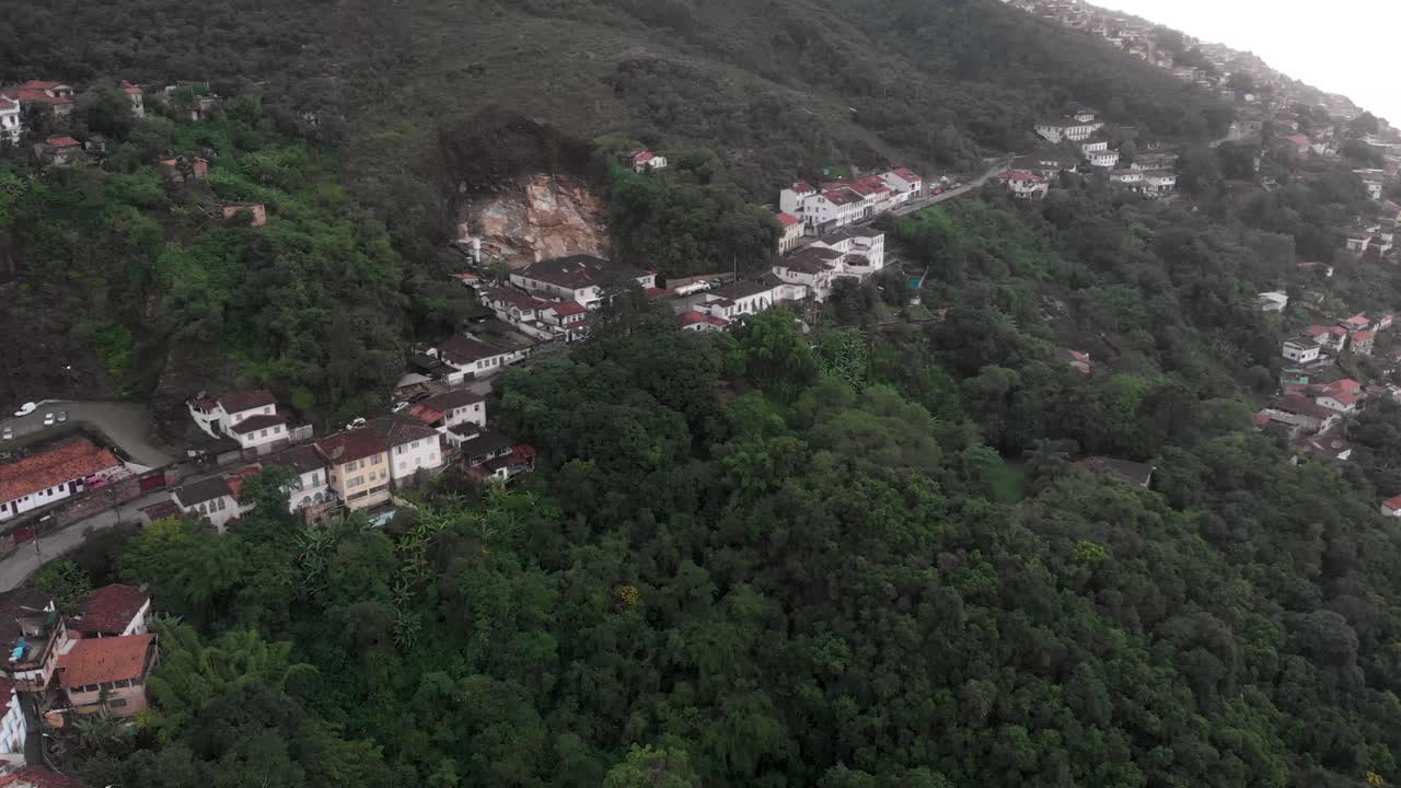 Main mountain road to mining city of Ouro Preto in Minas Gerais, revealing the valley and the central square of the Brazilian colonial gold capital with typical architecture on an overcast drowsy day