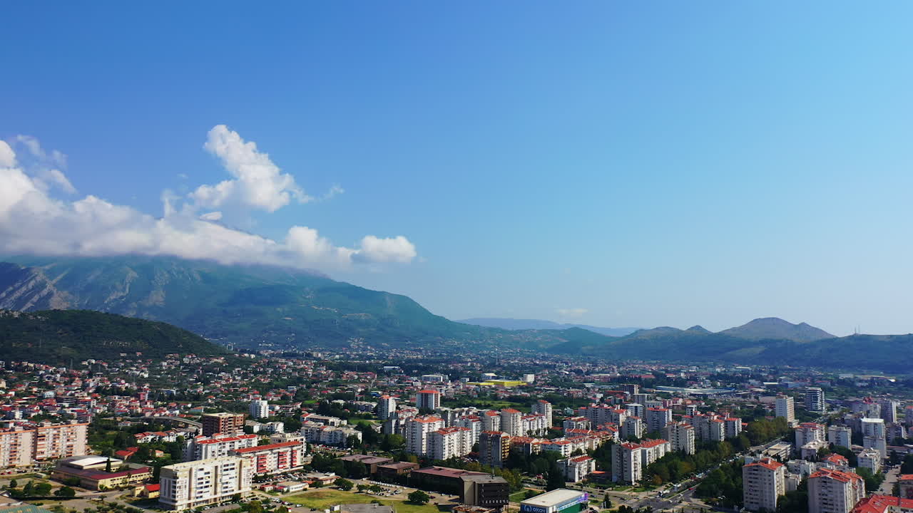 Lovely view of the sunny city that scattered among the mountains and the sea. Bar, Montenegro from aerial perspective.