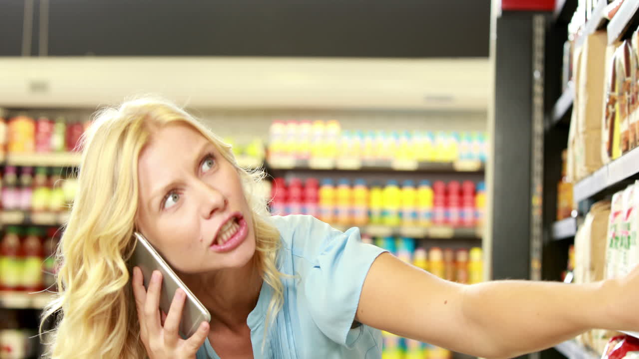 예쁜 금발이 전화하는 동안 제품을 찾고 있습니다.