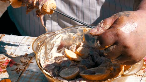 fat man puts the pickled meat on a skewer for a shish kebab