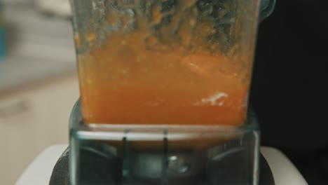 closeup of blender blades as it starts to mix white and orange ingredients